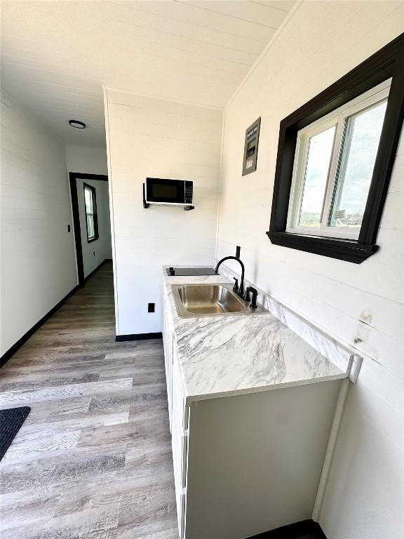 kitchen with light wood-style floors, baseboards, light countertops, and a sink