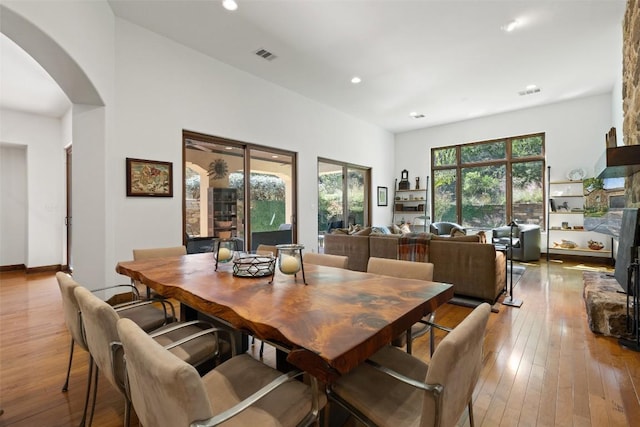 dining space with a stone fireplace and light hardwood / wood-style flooring