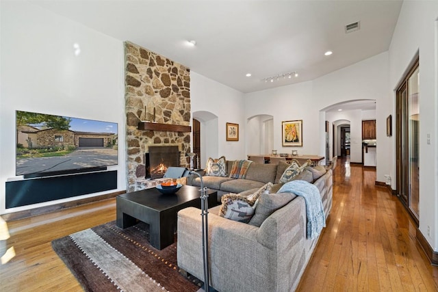 living room with a stone fireplace and light hardwood / wood-style flooring