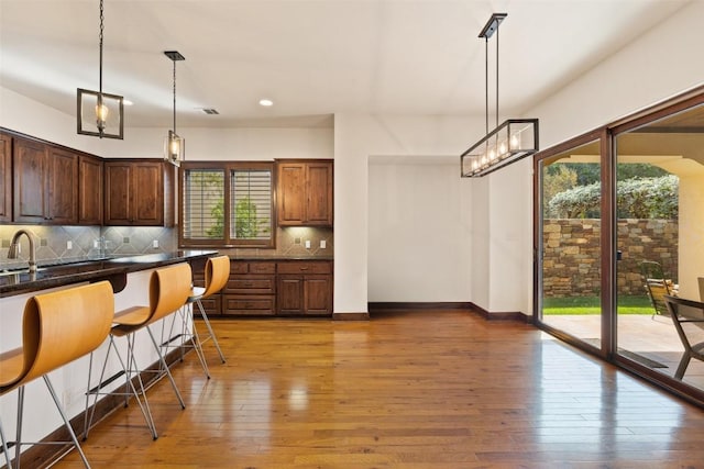 kitchen featuring hardwood / wood-style flooring, decorative light fixtures, and a breakfast bar area