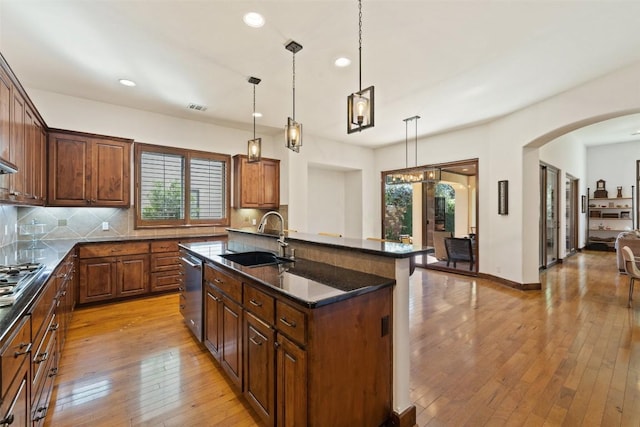 kitchen with pendant lighting, appliances with stainless steel finishes, an island with sink, and sink