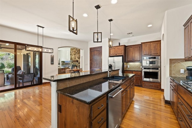 kitchen featuring appliances with stainless steel finishes, pendant lighting, sink, dark stone counters, and a large island