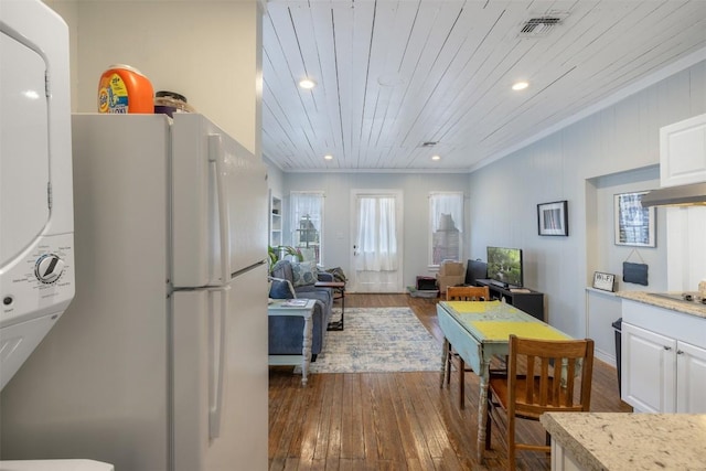 dining area with dark hardwood / wood-style flooring, crown molding, wooden ceiling, and stacked washer and clothes dryer