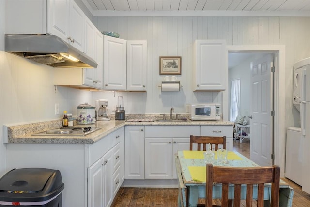 kitchen featuring sink, stacked washer and clothes dryer, and white cabinets