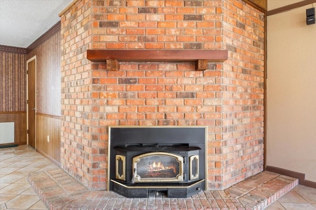 interior details featuring ornamental molding, a wood stove, wooden walls, and a textured ceiling