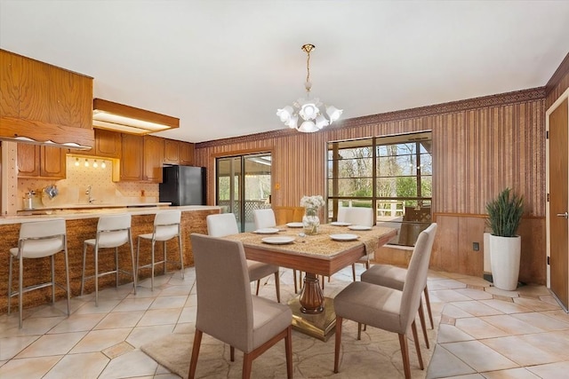 dining space featuring wood walls, light tile patterned floors, and a notable chandelier