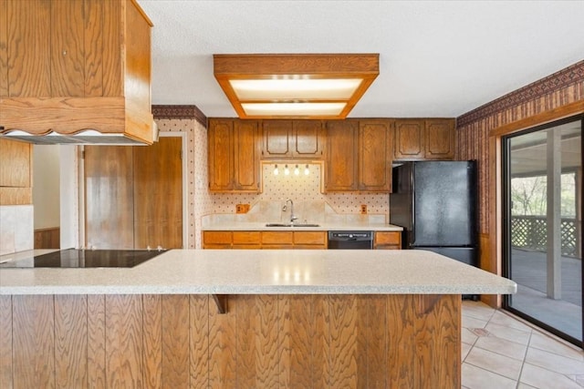 kitchen featuring premium range hood, sink, light tile patterned floors, kitchen peninsula, and black appliances