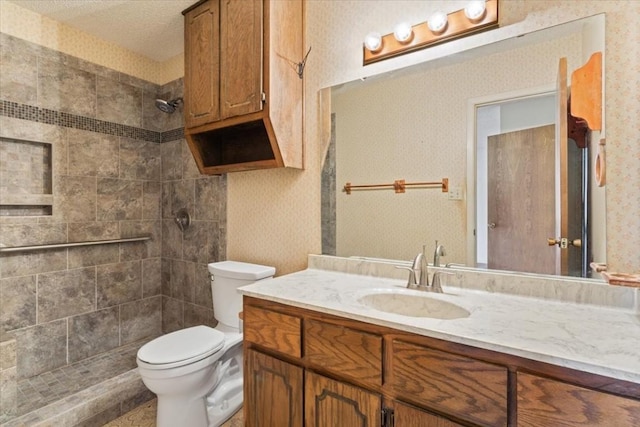 bathroom with vanity, toilet, and a tile shower