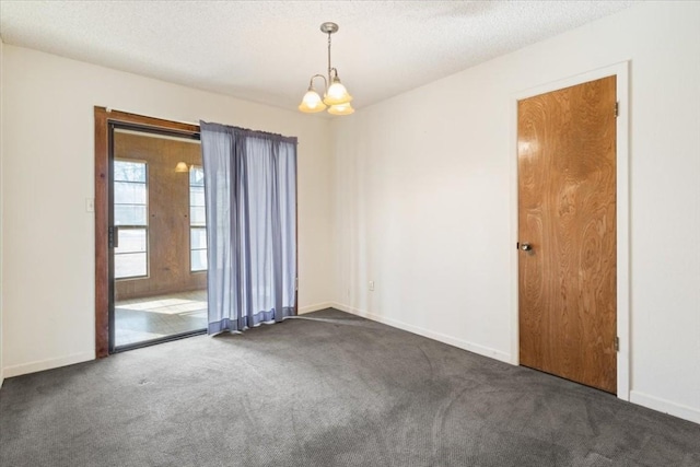 unfurnished room with dark carpet, a chandelier, and a textured ceiling