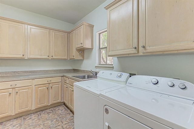 clothes washing area featuring cabinets, sink, and washer and clothes dryer