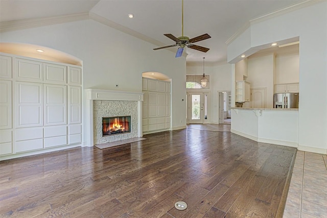 unfurnished living room with ornamental molding, wood-type flooring, high vaulted ceiling, and ceiling fan