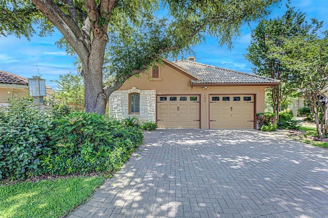 106 Mason Ct E, Horseshoe Bay, TX 78657 - view of front of property featuring stucco siding, a garage, a chimney, decorative driveway, and stone siding
