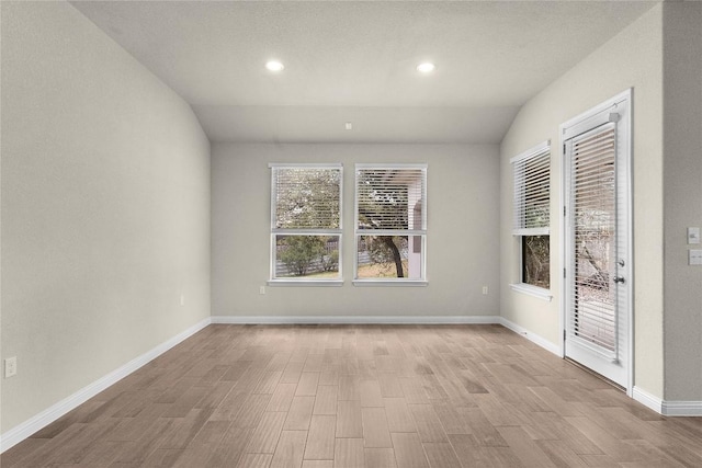 unfurnished room with lofted ceiling and light hardwood / wood-style floors