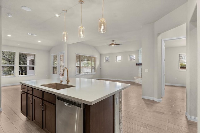 kitchen featuring dark brown cabinetry, sink, stainless steel dishwasher, and an island with sink