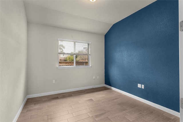 empty room with vaulted ceiling and light hardwood / wood-style floors