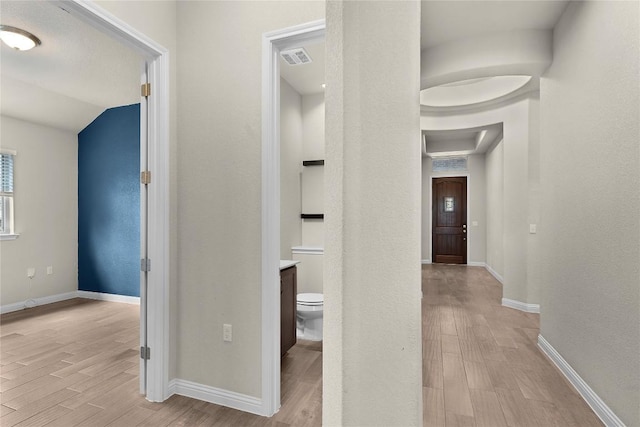 hallway with vaulted ceiling and light hardwood / wood-style floors