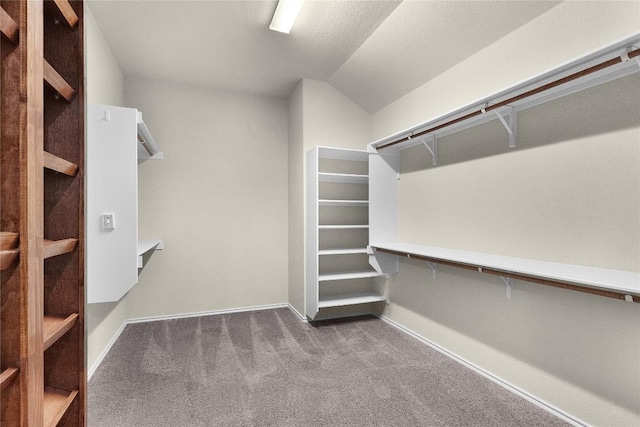 walk in closet with lofted ceiling and dark colored carpet