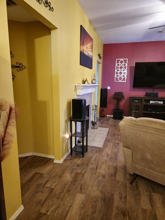 living room with a fireplace with flush hearth, wood finished floors, and baseboards