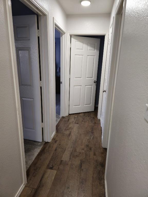 hall with dark wood-style floors and a textured wall