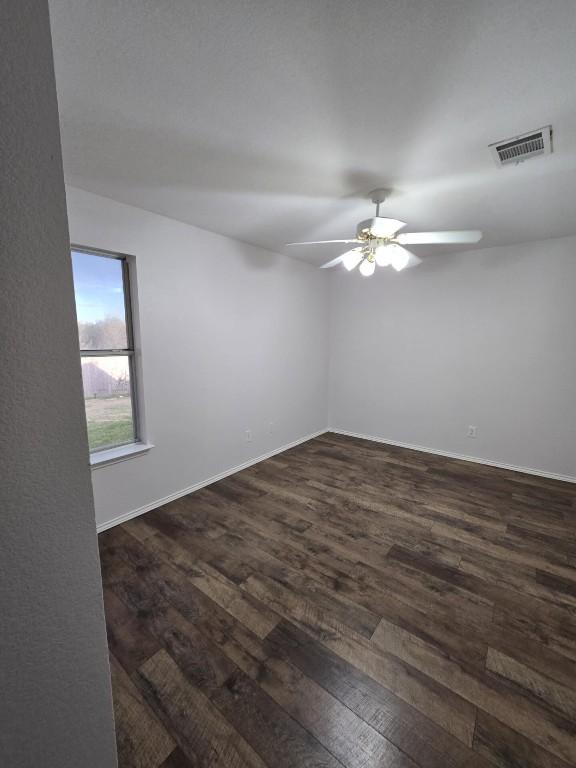 211 Valley Run Trl, Elgin, TX 78621 - empty room with dark wood-style floors, visible vents, a ceiling fan, and baseboards