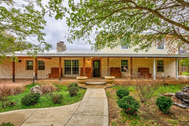 1000 Ledbetter St, Round Rock, TX 78681 - view of front facade featuring stone siding, a chimney, a metal roof, and a porch
