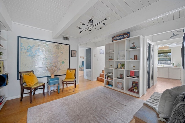 living area featuring beam ceiling, light hardwood / wood-style floors, and wooden ceiling