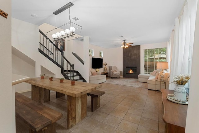 interior space with tile patterned flooring, ceiling fan with notable chandelier, and a large fireplace