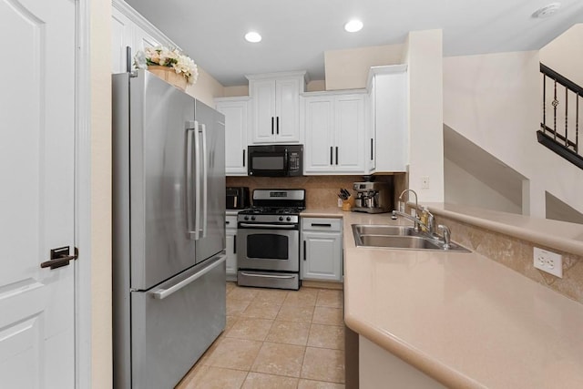 kitchen with sink, light tile patterned floors, appliances with stainless steel finishes, white cabinetry, and tasteful backsplash