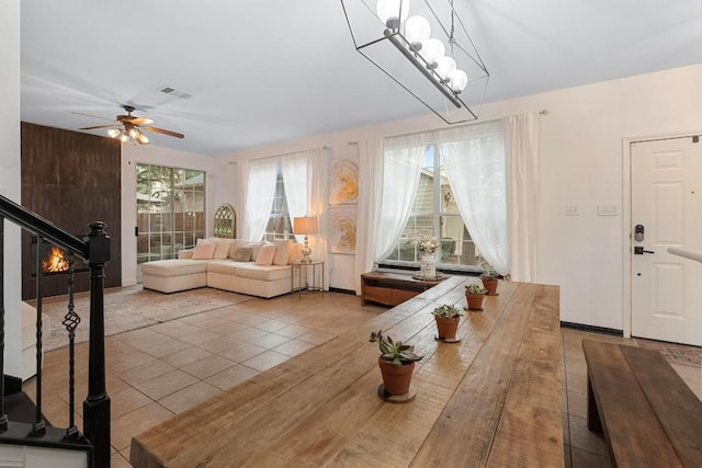 tiled dining area with ceiling fan with notable chandelier