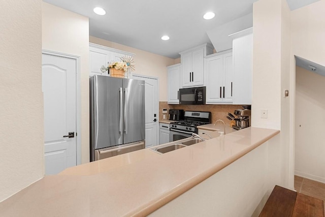 kitchen with sink, white cabinetry, stainless steel appliances, tasteful backsplash, and kitchen peninsula