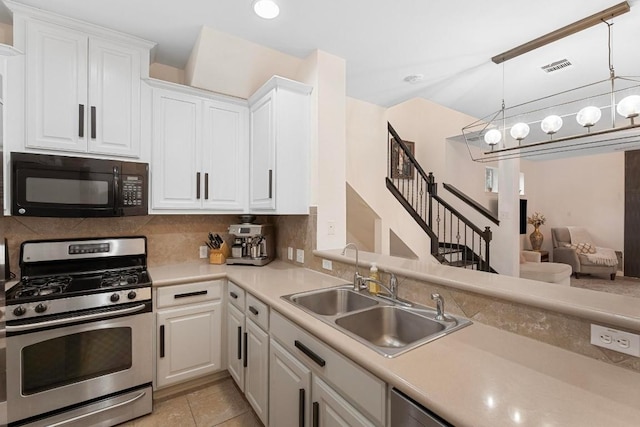 kitchen with sink, stainless steel gas stove, hanging light fixtures, tasteful backsplash, and white cabinets