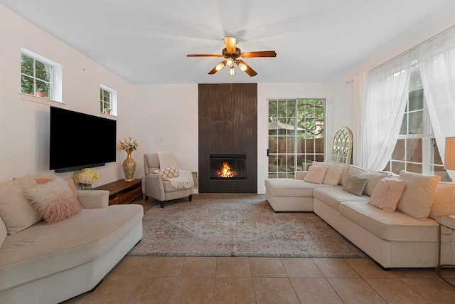 tiled living room featuring ceiling fan, plenty of natural light, and a fireplace