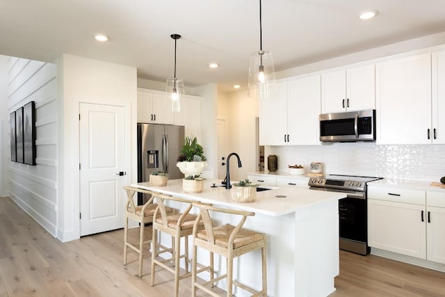 kitchen with white cabinetry, appliances with stainless steel finishes, a kitchen island with sink, and sink