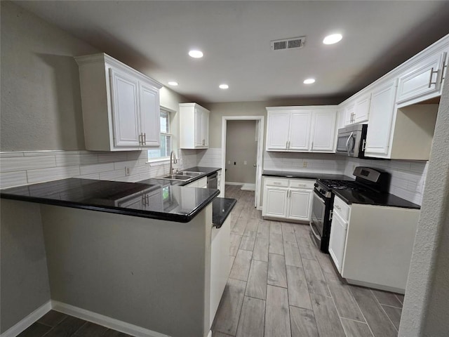 177 E Davilla St, Bartlett, TX 76511 - kitchen with stainless steel appliances, visible vents, a sink, light wood-type flooring, and a peninsula