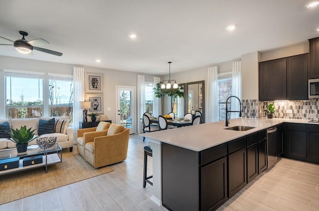 kitchen with dishwashing machine, sink, a kitchen bar, decorative light fixtures, and kitchen peninsula