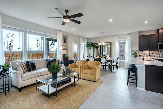 living room featuring sink and ceiling fan with notable chandelier