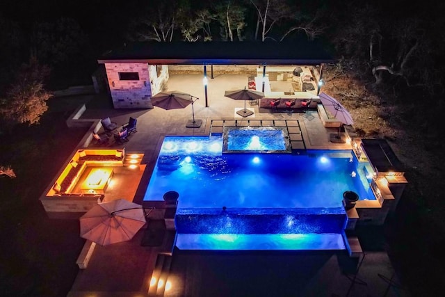 pool at twilight featuring a fire pit, a jacuzzi, and a patio area