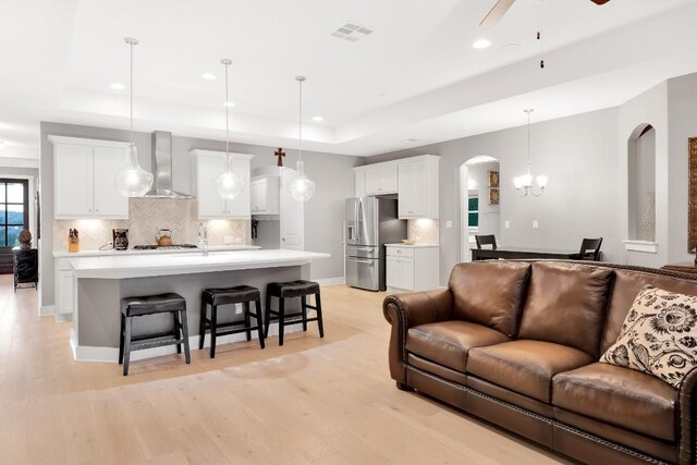 197 Bristlecone Dr, Driftwood, TX 78619 - living room featuring a tray ceiling, arched walkways, recessed lighting, light wood finished floors, and ceiling fan