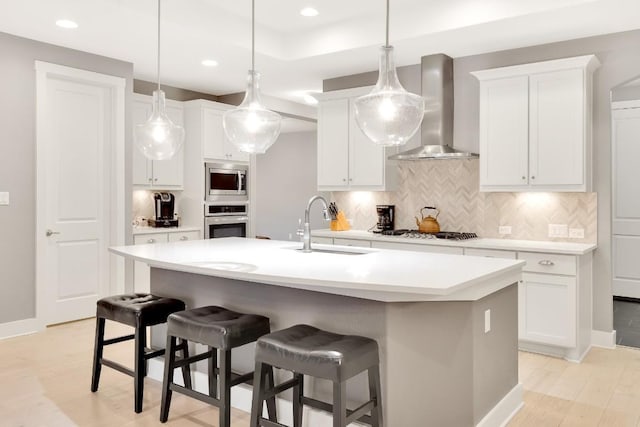 kitchen with white cabinetry, sink, wall chimney exhaust hood, and appliances with stainless steel finishes