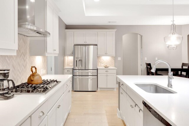 197 Bristlecone Dr, Driftwood, TX 78619 - kitchen with appliances with stainless steel finishes, range hood, a sink, light countertops, and hanging light fixtures