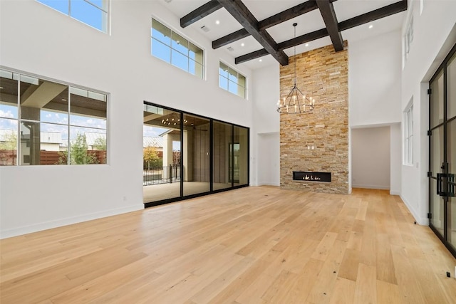 unfurnished living room featuring a notable chandelier, a fireplace, light hardwood / wood-style floors, and beamed ceiling