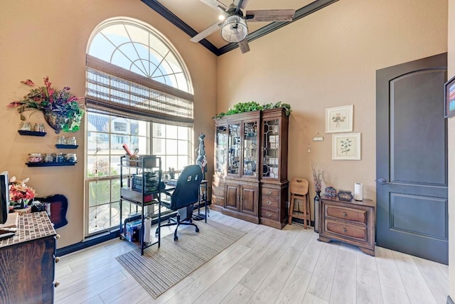 home office with crown molding, light hardwood / wood-style floors, ceiling fan, and a high ceiling