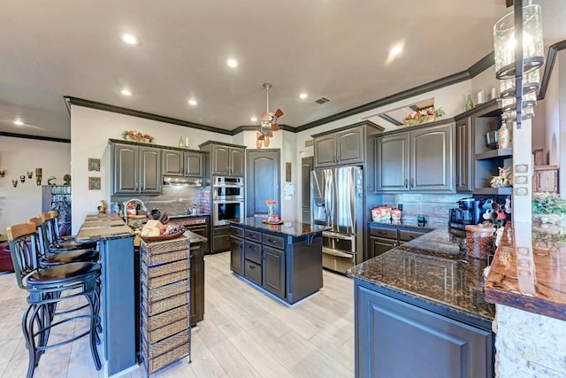 kitchen with appliances with stainless steel finishes, dark stone countertops, backsplash, a center island, and kitchen peninsula