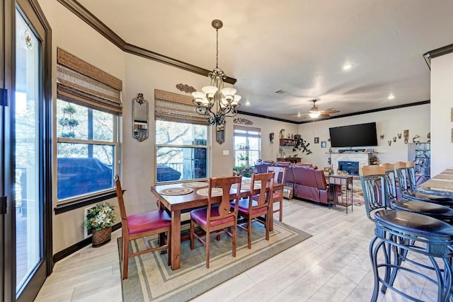 dining space featuring ornamental molding, ceiling fan with notable chandelier, and light wood-type flooring