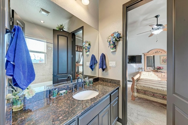 bathroom with ceiling fan, vanity, and a textured ceiling