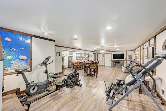 workout area with ornamental molding, light hardwood / wood-style floors, and ceiling fan