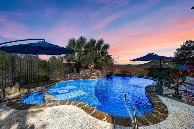 pool at dusk featuring a patio