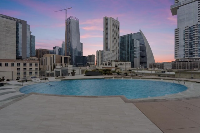 pool at dusk featuring a patio