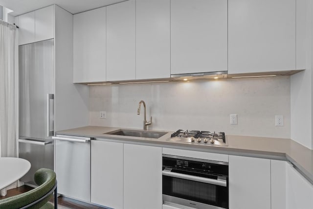 kitchen with white cabinetry, sink, decorative backsplash, and stainless steel appliances