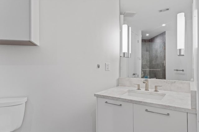 bathroom with vanity, a shower with door, and toilet